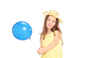 Cute little girl in yellow dress holding a blue balloon