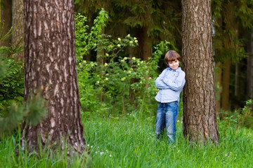 Naklejka na ściany i meble Little boy playing in a beautiful forest