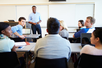 Male Tutor Teaching University Students In Classroom