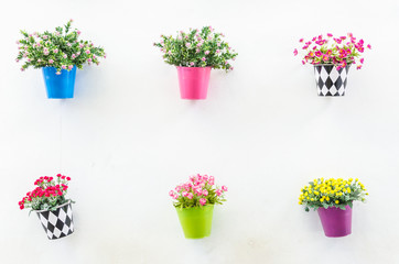 Plastic flower in vase on wall background