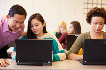 High School Students With Teacher In Class Using Laptops