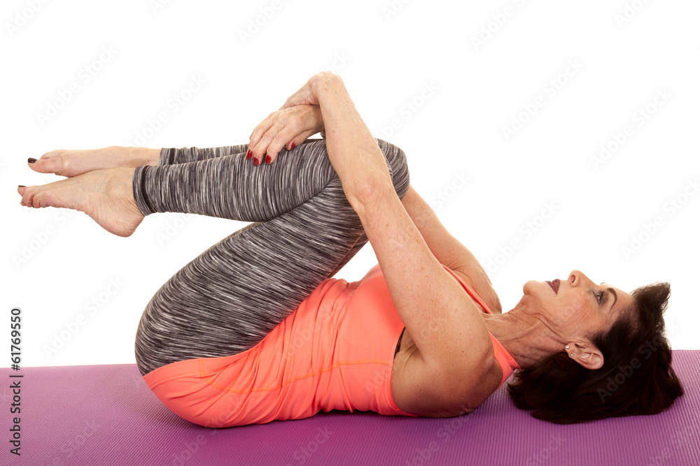 Wall mural older woman yoga on back curl knees