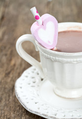 hot chocolate and heart-shaped marshmallow on wooden surface