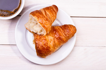 Coffee cup with a croissant isolated on wooden table 