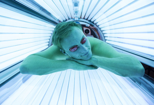 Man with sunglasses on tanning bed in solarium