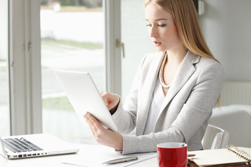 Attractive business woman is typing on her tablet