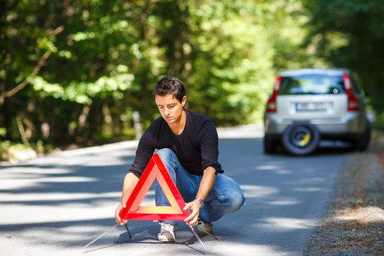 Handsome young man with his car broken down by the roadside