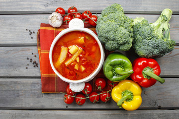 Top view of red tomato soup on wooden table. Fresh vegetables