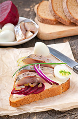 Sandwich of rye bread with herring, beets, onions and egg