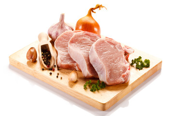 Raw pork on cutting board and vegetables