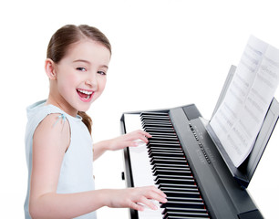 Smiling girl plays on the electric piano.