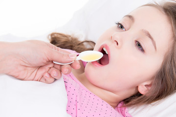 Little girl with sore throat using cough syrup.