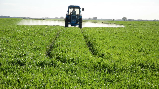 Tractor spray fertilize field with pesticide chemicals