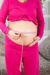 Pregnant woman measuring her growing