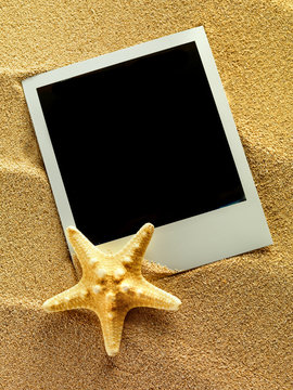 Vintage empty photo frames are lying on the sea sand decorated w