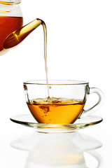 Tea pouring into glass cup isolated in white