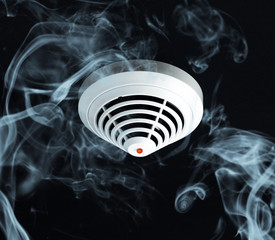 Smoke around fire detector on black background.