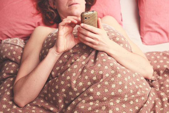 Young woman texting in bed