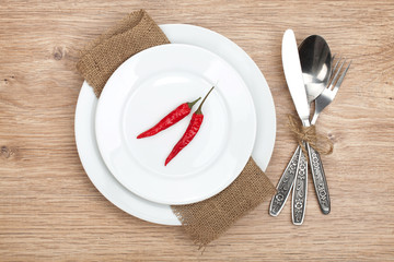 Red chili peppers on plate and silverware set - Powered by Adobe