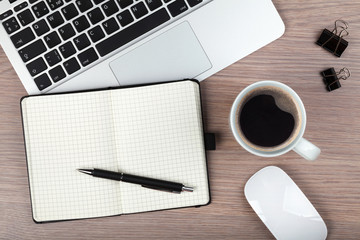 Notepad, laptop and coffee cup on wood table