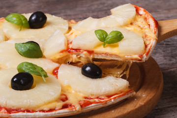 Slice of pizza with pineapple, cheese and black olives, basil