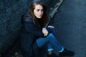 Pretty lonely girl sitting on asphalt