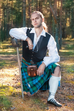 Handsome scottish man with sword and pipe