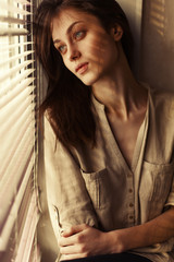 Obraz premium Beautiful cute girl home alone near the window