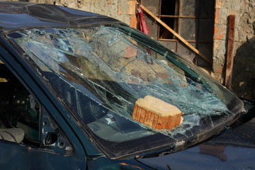 Broken green car with a brick on the windshield
