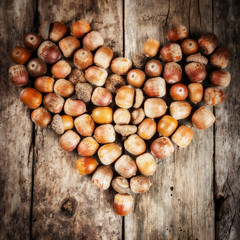 Acorns forming a heart on a wooden background
