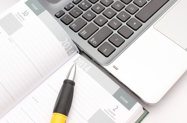 Pen on calendar and laptop keyboard