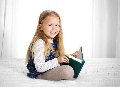 happy cute blonde haired school girl reading a book