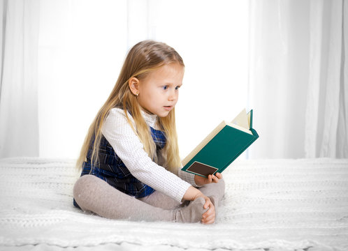 scared cute blonde haired school girl reading a book