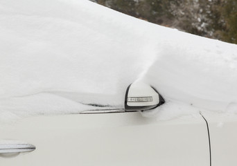 Deep snow on top of white car in drive