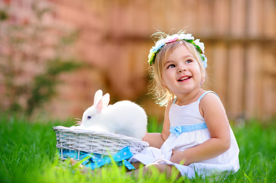 Cute little girl with a bunny rabbit has a easter at green grass