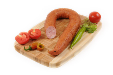 Sausages with a tomato and pepper on cutting board