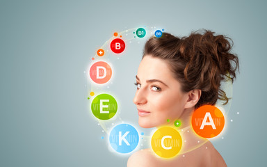 Pretty young girl with colorful vitamin icons and symbols
