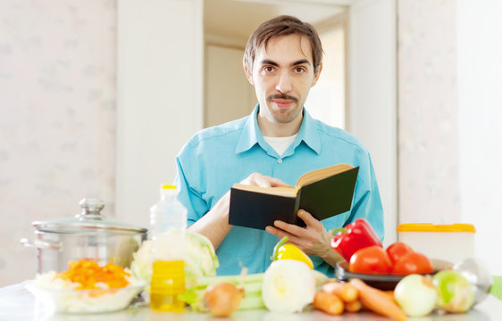 Portrait of man with cookbook in domestic kitchen