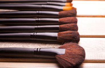 Set of black make-up brushes in row on the wooden table