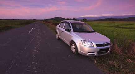 Plakat Car parked on roadside in a rural area at sunset