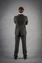 Young businessman full body portrait from behind against grunge