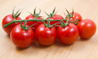 Tomatoes cherry civered by water drops on a wooden board