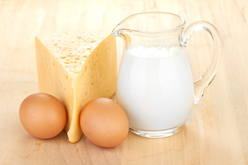 Big piece of cheese, glass jug with milk