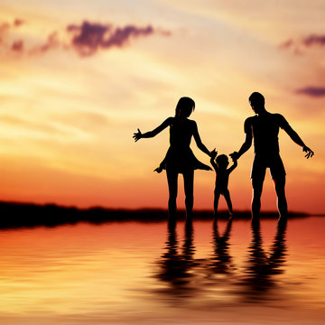 Happy family walking together hand in hand at sunset