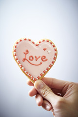 Hand holds pastry with white cream heart