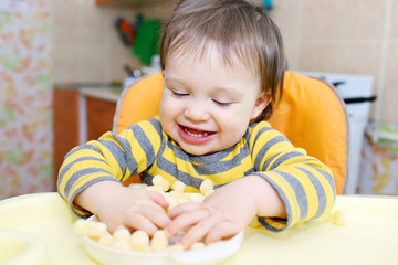happy baby playing with corn curls