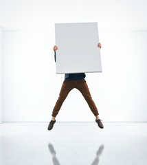 Man jumping with blank poster in his hands