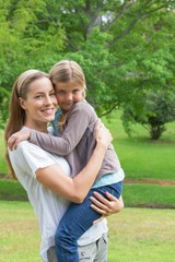 Fototapeta premium Smiling mother carrying daughter at park