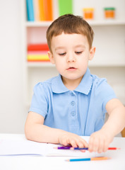 Naklejka premium Little boy is drawing on white paper