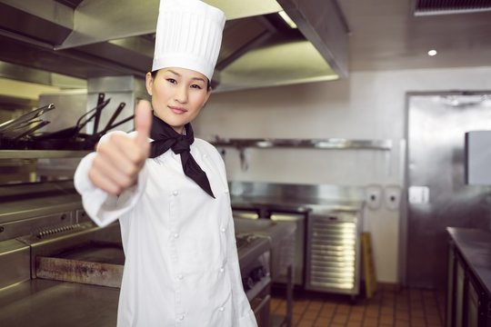 Female cook gesturing thumbs up in kitchen